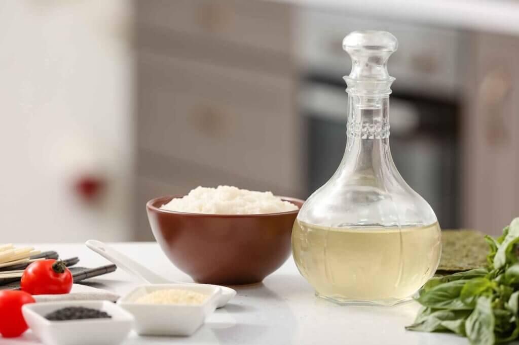 Glass bottle of rice vinegar displayed with rice and fresh ingredients