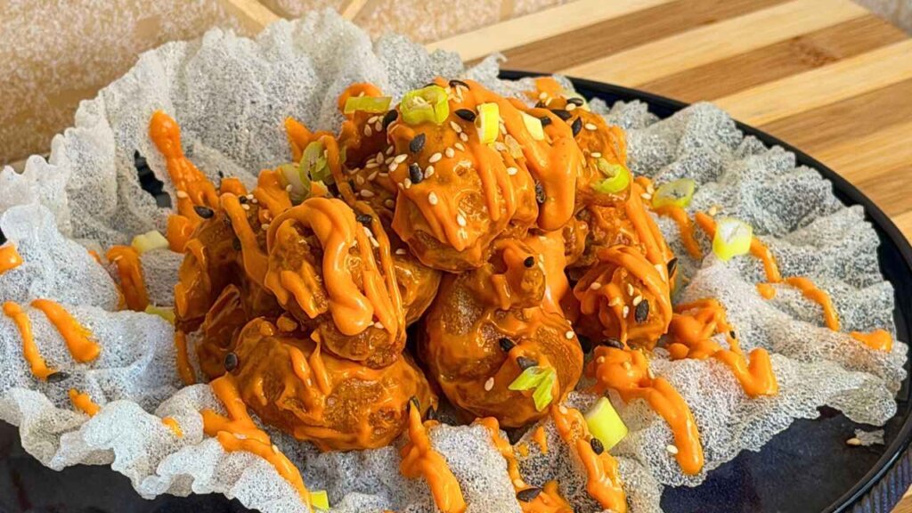 Dynamite shrimps coated in orange sauce, topped with sesame seeds and spring onions, served on fried rice paper.