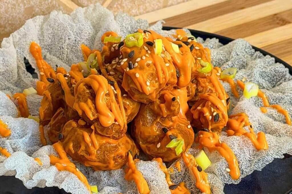 Dynamite shrimps coated in orange sauce, topped with sesame seeds and spring onions, served on fried rice paper.
