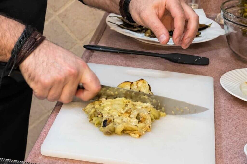 Chef François chopping peeled roasted eggplant on a white cutting board to prepare eggplant mtabbal.